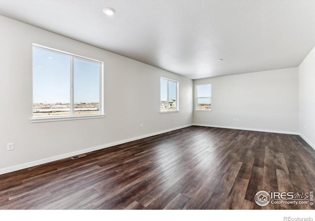 empty room featuring dark wood-type flooring and plenty of natural light