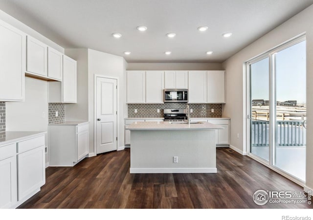 kitchen with a kitchen island with sink, dark hardwood / wood-style floors, white cabinets, and appliances with stainless steel finishes