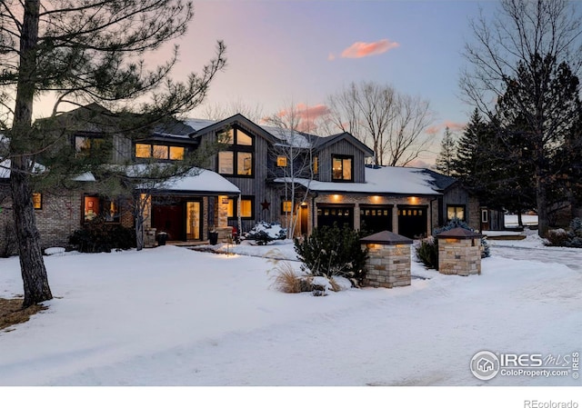 snow covered back of property featuring a garage