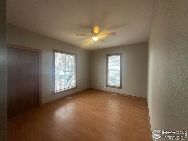 unfurnished room featuring a wealth of natural light, hardwood / wood-style floors, and ceiling fan