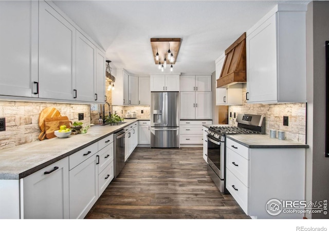 kitchen featuring sink, appliances with stainless steel finishes, white cabinets, decorative backsplash, and custom exhaust hood