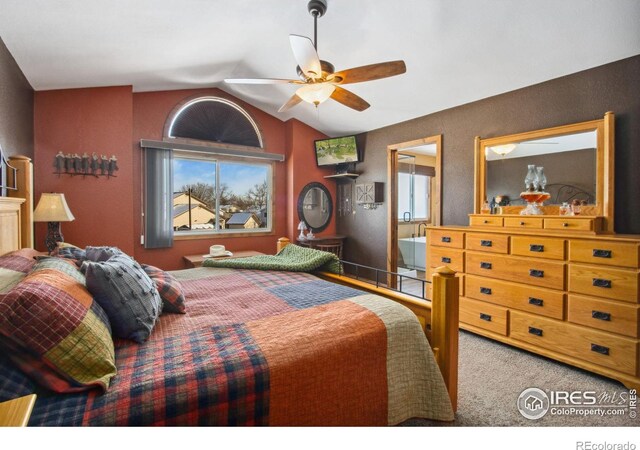 bedroom featuring carpet floors, ensuite bathroom, ceiling fan, and vaulted ceiling