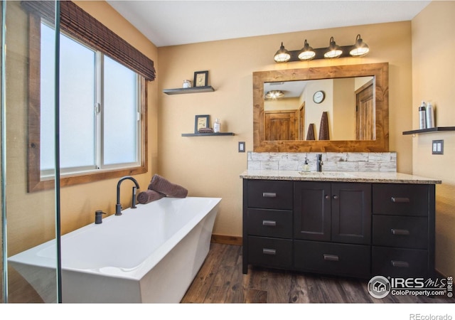 bathroom featuring vanity, a bath, and wood-type flooring