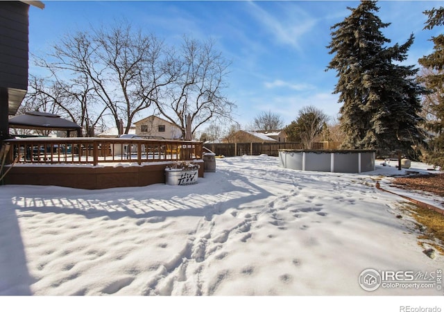 yard covered in snow with a pool side deck