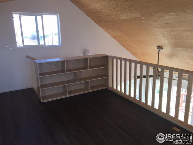 additional living space with dark hardwood / wood-style floors and vaulted ceiling