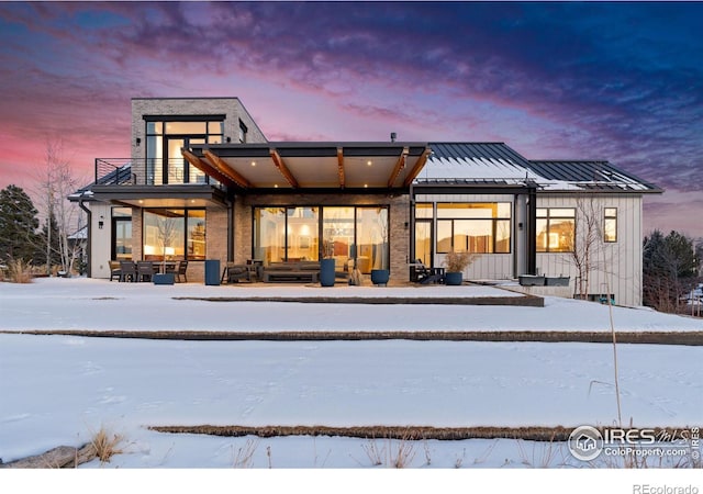 snow covered house featuring a balcony