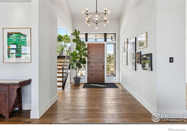 foyer with vaulted ceiling, dark hardwood / wood-style floors, and a chandelier