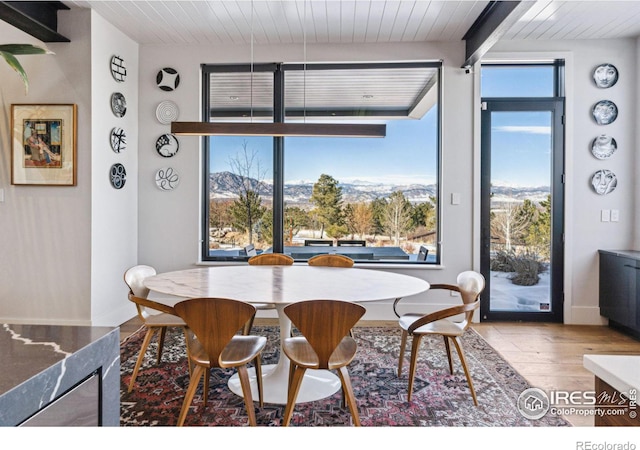 dining space featuring beam ceiling, a mountain view, wood ceiling, and light hardwood / wood-style floors