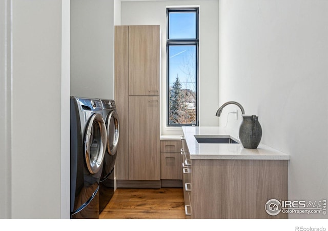 laundry room with sink, washing machine and clothes dryer, and light hardwood / wood-style flooring