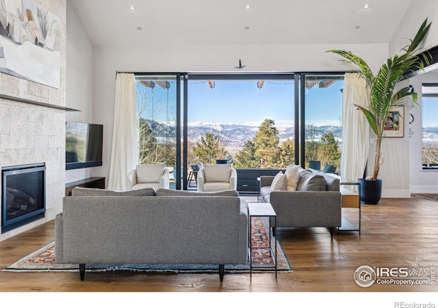 living area with recessed lighting, baseboards, wood finished floors, and a glass covered fireplace