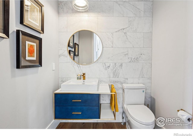 bathroom with tile walls, vanity, toilet, and wood finished floors