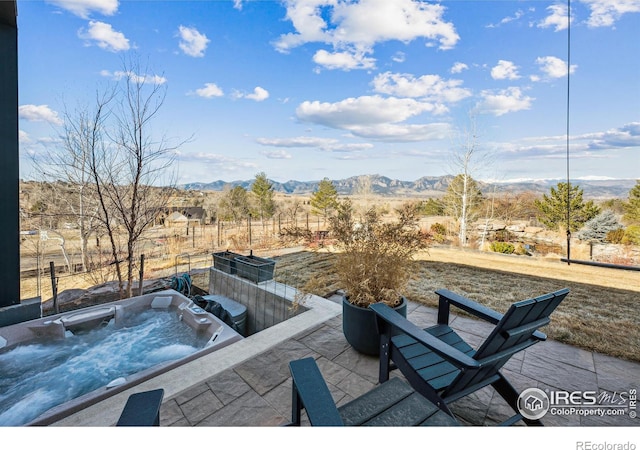 view of patio with a mountain view and a hot tub