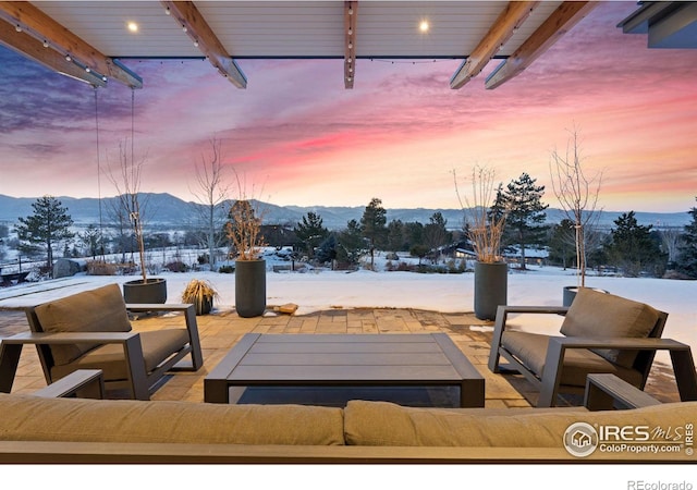 snow covered patio with outdoor lounge area and a mountain view