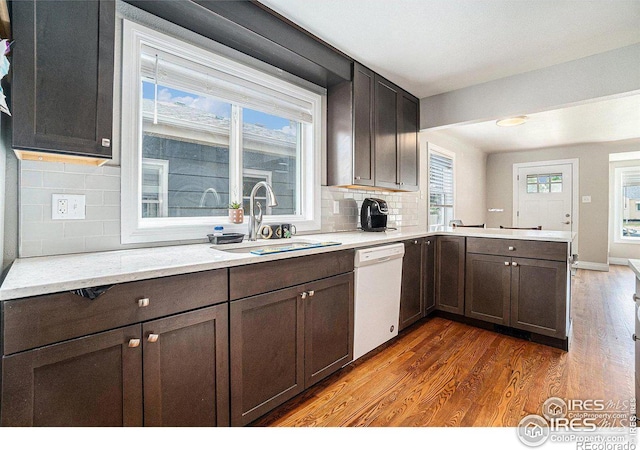 kitchen with dark brown cabinetry, sink, tasteful backsplash, dark hardwood / wood-style floors, and white dishwasher