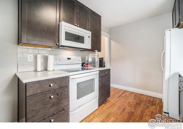 kitchen with white appliances, dark brown cabinetry, dark hardwood / wood-style floors, and decorative backsplash