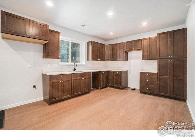 kitchen featuring dark brown cabinetry, sink, and light hardwood / wood-style flooring