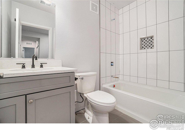 full bathroom with vanity, tiled shower / bath, tile patterned floors, and toilet