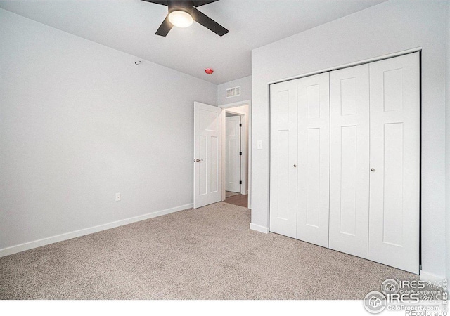 unfurnished bedroom with light colored carpet, ceiling fan, and a closet