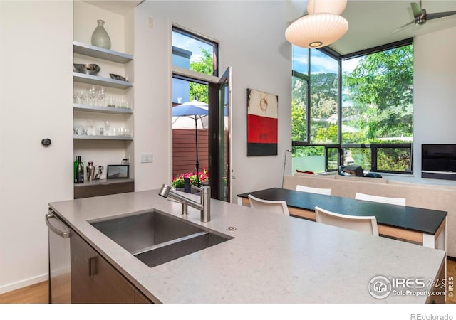 kitchen featuring sink, built in features, dishwasher, hardwood / wood-style floors, and light stone countertops