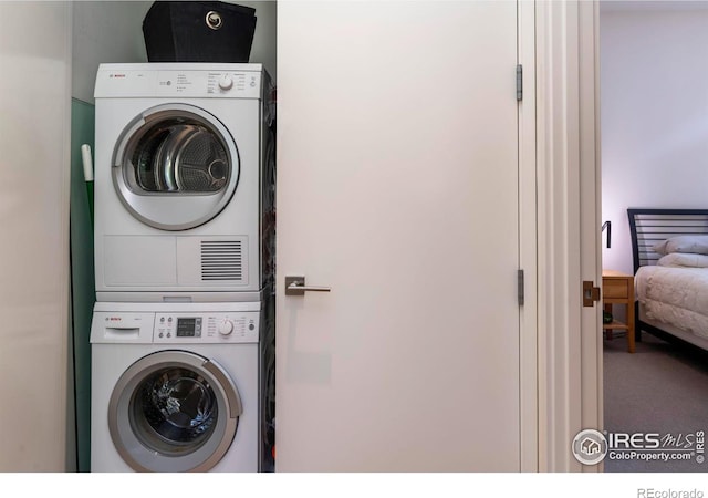 clothes washing area featuring carpet and stacked washer / dryer