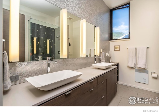 bathroom with vanity, a shower with shower door, tile patterned flooring, and decorative backsplash