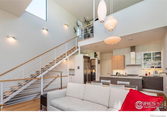 living room featuring a towering ceiling, sink, and light hardwood / wood-style floors