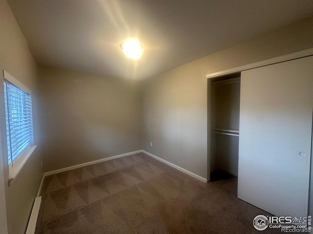 unfurnished bedroom featuring dark carpet and a closet