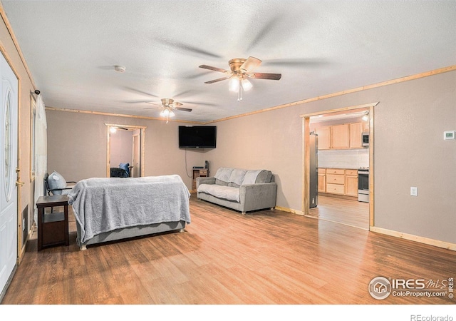 bedroom with ornamental molding, stainless steel fridge, light hardwood / wood-style flooring, and a textured ceiling