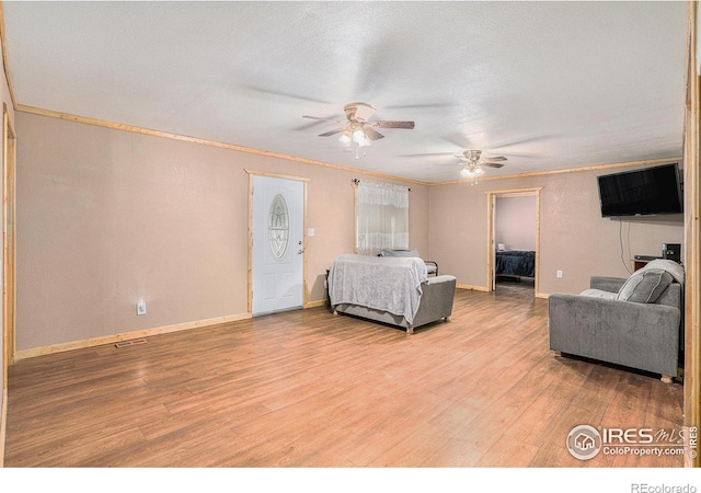 bedroom with ornamental molding, a textured ceiling, ceiling fan, and light hardwood / wood-style flooring