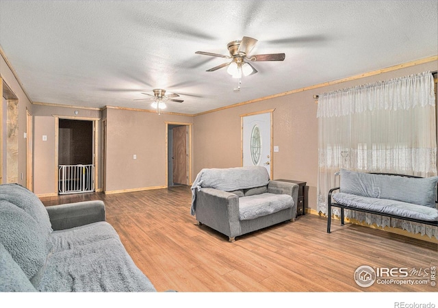 living room with ceiling fan, ornamental molding, wood-type flooring, and a textured ceiling