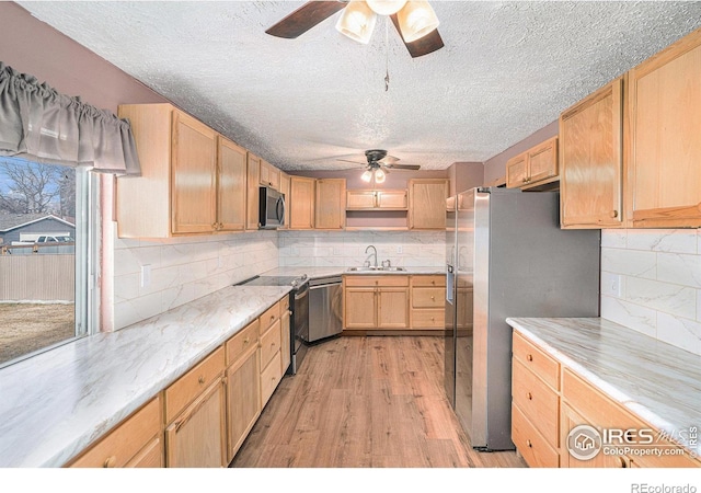 kitchen with light brown cabinetry, sink, light hardwood / wood-style floors, and appliances with stainless steel finishes