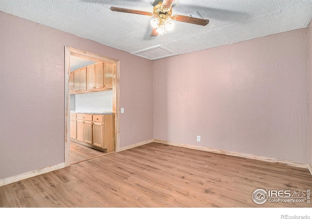 empty room with ceiling fan, light hardwood / wood-style flooring, and a textured ceiling