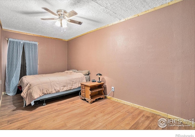 bedroom featuring hardwood / wood-style flooring, ornamental molding, ceiling fan, and a textured ceiling