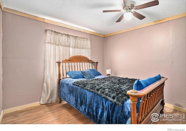 bedroom with ceiling fan, wood-type flooring, ornamental molding, and a textured ceiling