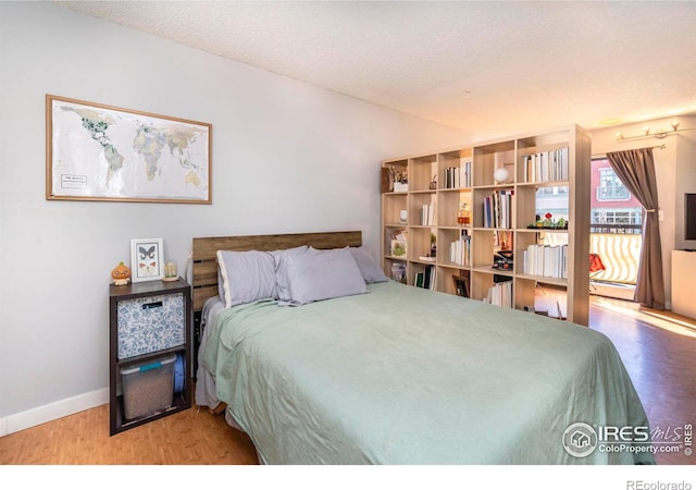 bedroom featuring hardwood / wood-style flooring, vaulted ceiling, and a textured ceiling