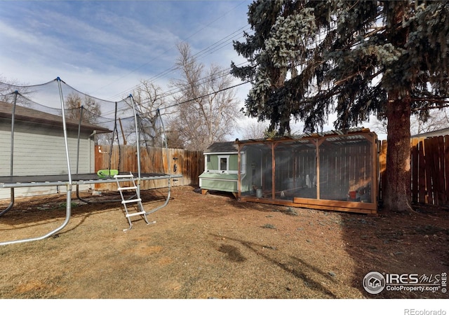 view of yard with a fenced backyard, a trampoline, exterior structure, and an outdoor structure