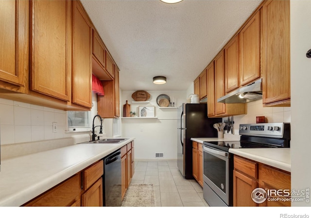 kitchen featuring brown cabinets, under cabinet range hood, stainless steel appliances, and a sink