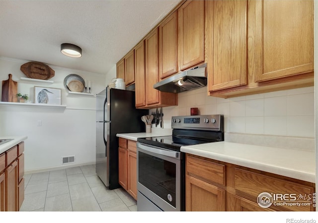 kitchen featuring visible vents, decorative backsplash, stainless steel appliances, light countertops, and under cabinet range hood