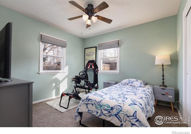 carpeted bedroom featuring ceiling fan, baseboards, and a textured ceiling