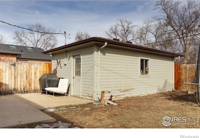 view of side of property with a patio area, a trampoline, and fence