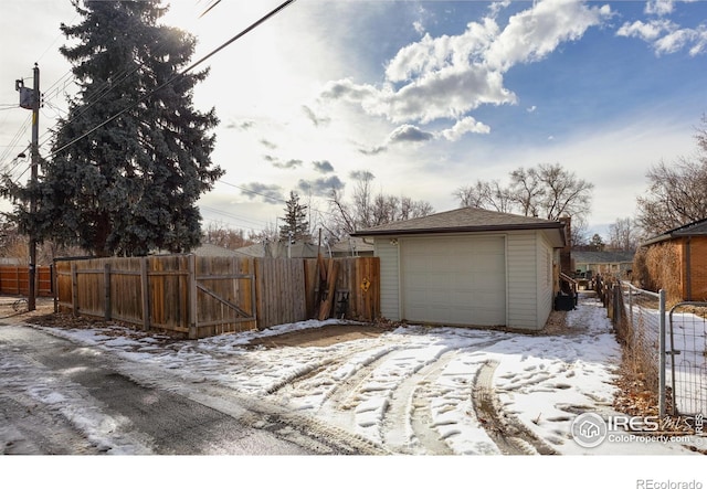 snow covered garage with a garage and fence