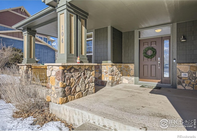 snow covered property entrance with covered porch