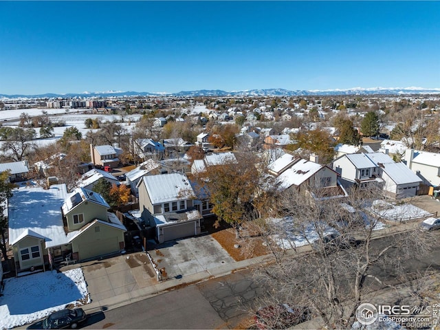 snowy aerial view featuring a mountain view and a residential view