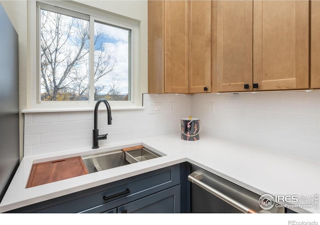 kitchen with a sink, backsplash, stainless steel dishwasher, and light countertops