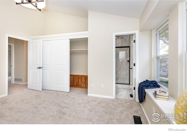 carpeted bedroom with a closet, baseboards, visible vents, and ensuite bath