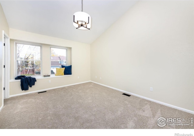 carpeted empty room with an inviting chandelier, lofted ceiling, baseboards, and visible vents