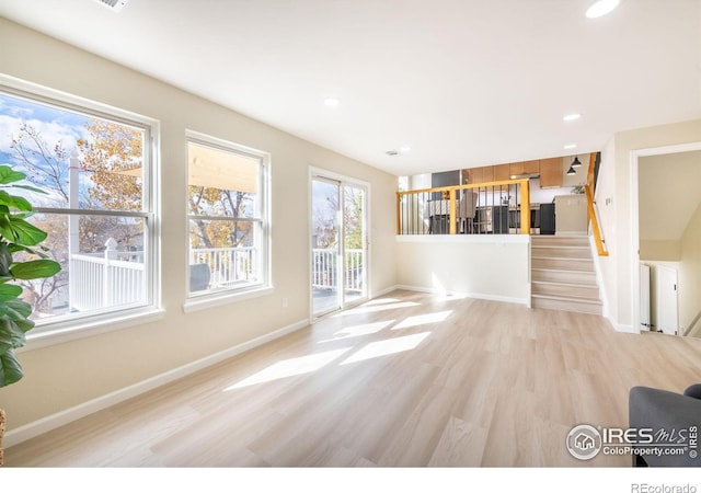 unfurnished living room with recessed lighting, baseboards, stairs, and light wood-style floors