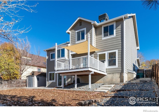 back of property with a storage unit, fence, an outdoor structure, a wooden deck, and stairs