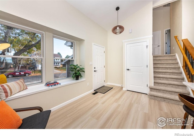 foyer entrance featuring stairway, baseboards, high vaulted ceiling, and wood finished floors