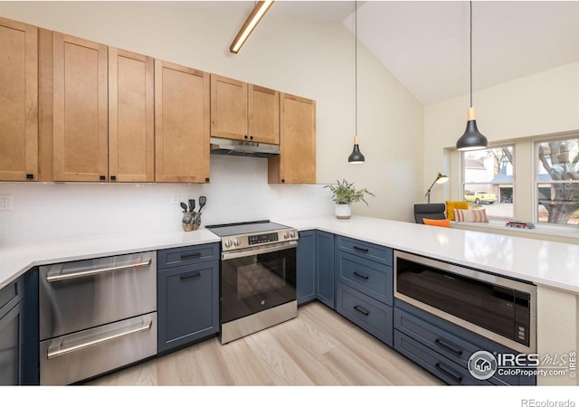 kitchen with under cabinet range hood, stainless steel appliances, light countertops, and vaulted ceiling